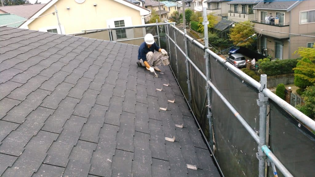 ストレート屋根を刷毛で塗っている職人