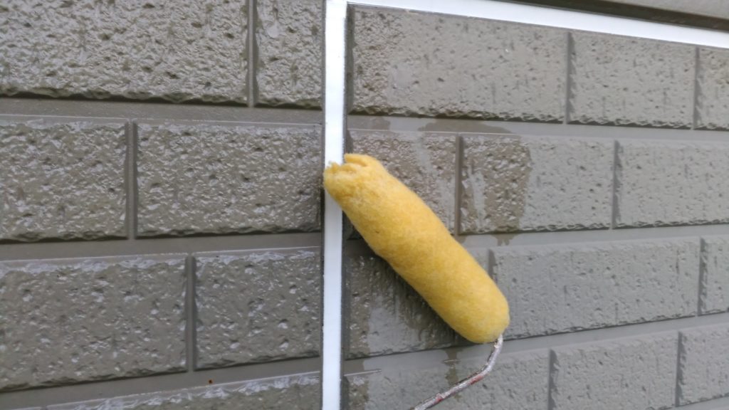 外壁をローラーで塗っている職人