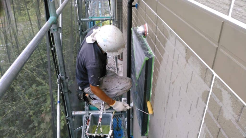 外壁をローラーで塗っている職人